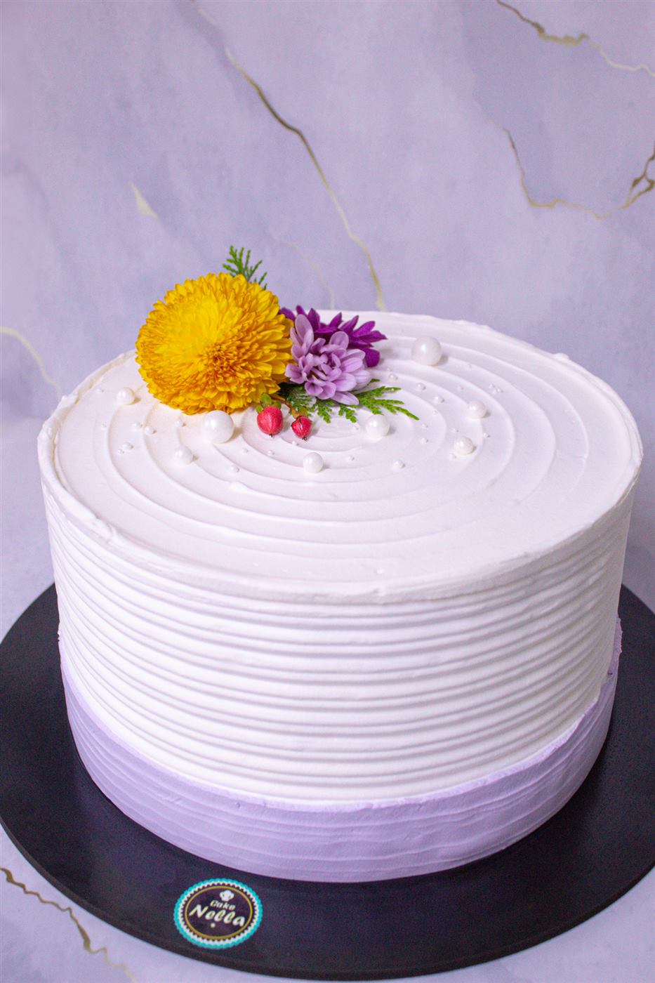 Torta blanca y lila con flores naturales
